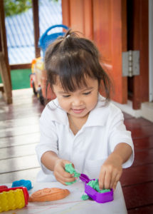 Little girl playing with play-doh smiling